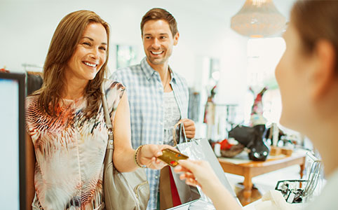 Vantagens do débito Imagem mostra um casal feliz pagando suas compras com o cartão de débito Itaú