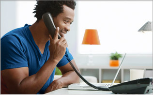 Fotografia de um homem falando ao telefone em sua sala de estar.